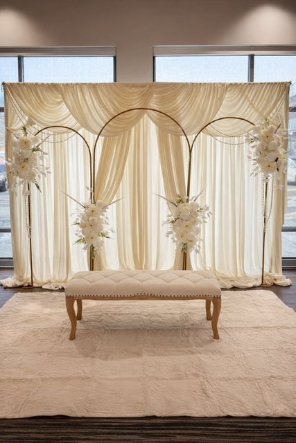 Backdrop elegante con cortinas marfil y arcos dorados