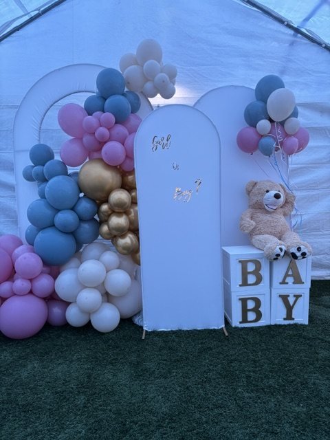 Gender reveal con globos rosa, azul y dorado y un osito