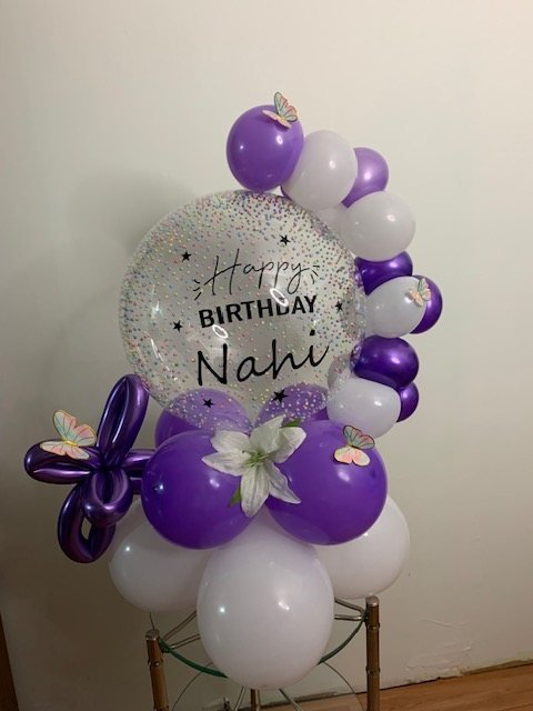 Arreglo de globos morados y blancos con burbuja “Happy Birthday Nahi” y mariposas
