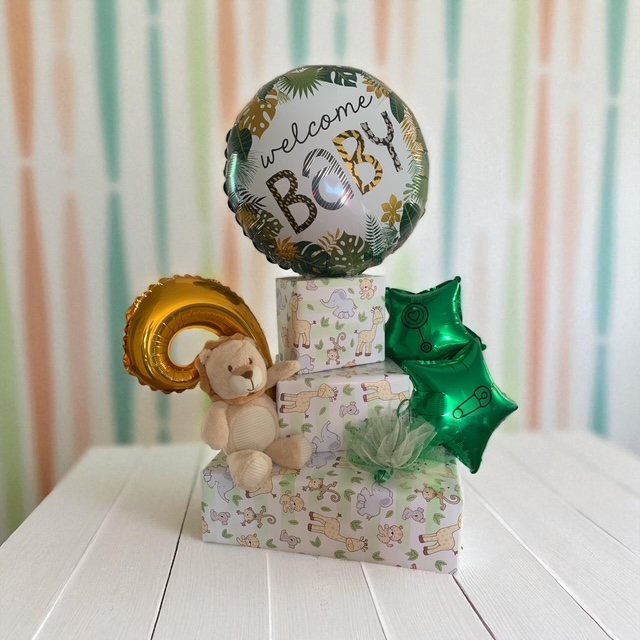 Regalo de bienvenida al bebé con cajas, osito y globos verdes y dorados
