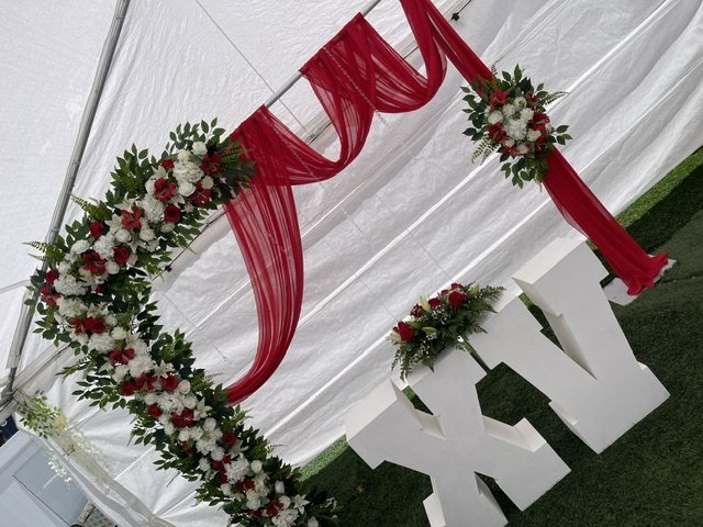 XV años en carpa con arco de rosas rojas y blancas, cortinas rojas y letras XV gigantes